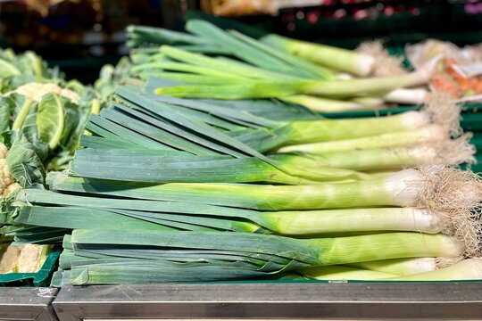 Large stalks of leeks lie on the counter in the supermarket. purchases vegetables greens