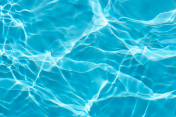 Blue water with ripples on the surface. Defocus blurred transparent blue colored clear calm water surface texture with splashes and bubbles. Water waves with shining pattern texture background.