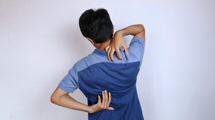 back view of asian young man itching in back area hand gesture scratching back