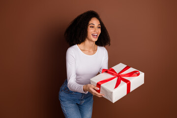 Photo of pretty young girl give giftbox empty space wear pullover isolated on brown color background