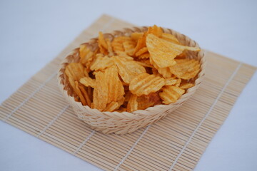 Crispy potato chips in a basket on white background.