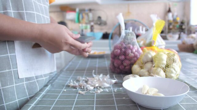 Woman peeling the garlics prepare for cook in the kitchen