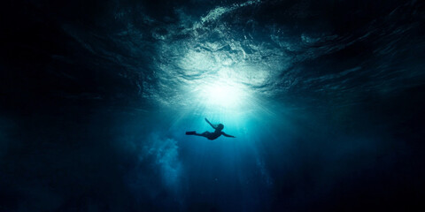 Fototapeta premium A swimmer gliding through tranquil deep blue water beneath shimmering sunlight