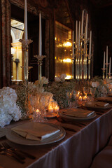 Modern luxury destination wedding decor in dark gold mode in historical Italian villa Arvedi with candelabras, gold chairs flowers and artworks