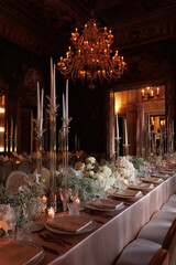 Modern luxury destination wedding decor in dark gold mode in historical Italian villa Arvedi with candelabras, gold chairs flowers and artworks