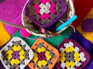 Crochet granny square, clews and hook on knitted blanket background photo