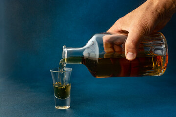 A man's hand pours whiskey into a glass.