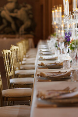 Modern luxury destination wedding decor in dark gold mode in historical Italian villa Arvedi with candelabras, gold chairs flowers and artworks