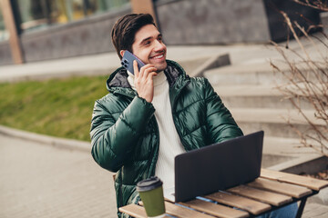 Obraz premium Photo of cheerful attractive man in trendy coat sitting on cafe terrace speaking phone pastime autumn day outdoors