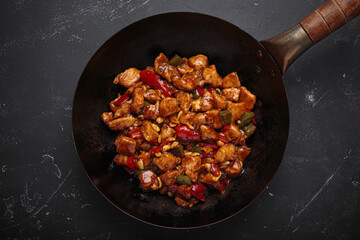 Wok is filled with savory kung pao chicken with tender chicken, crunchy peanuts and vibrant vegetables, all coated in a flavorful sauce