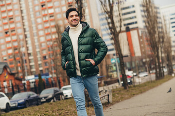 Photo of handsome cheerful dreamy man wearing trendy clothes walk alone in urban park autumn day...