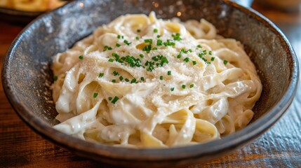 A delightful presentation of creamy Alfredo fettuccine pasta, garnished with fresh chives and served in a rustic bowl, creating a warm and inviting atmosphere for a comforting meal.