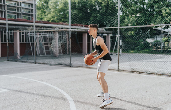 Friends playing basketball at an old neighborhood court, capturing a moment of fun, teamwork, and nostalgia in the sun.