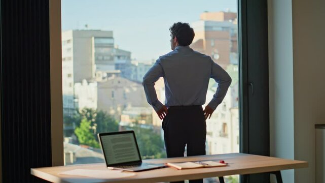 Pensive employee looking city view standing modern office. Serious businessman
