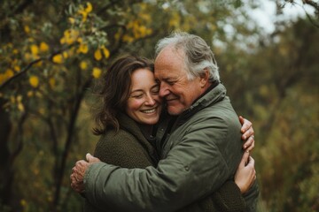 Obraz premium Warm embrace of joyful elderly couple in autumn forest setting