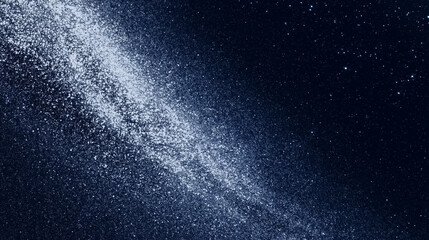Obraz premium A swirl of white particles spreading against a deep blue sky, resembling the Milky Way. The image evokes a sense of vastness and wonder, symbolizing space exploration and mystery.