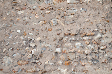 Weathered old stone wall with pebbles and mortar