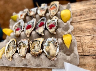 Fresh opened oysters, ice and lemon on a stone textured background.