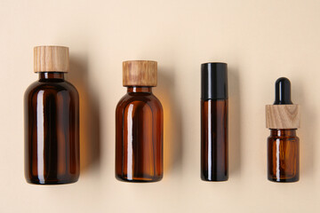 Essential oils in bottles on beige background, flat lay