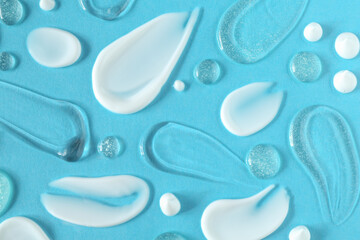 Smears of different cosmetic products on light blue background, flat lay