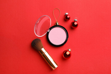 Blusher in shape of Christmas ball and brush on red background, flat lay