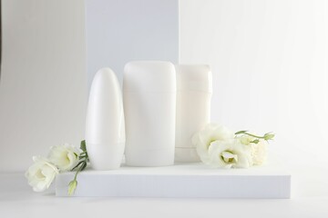 Different deodorants and beautiful eustoma flowers on white background
