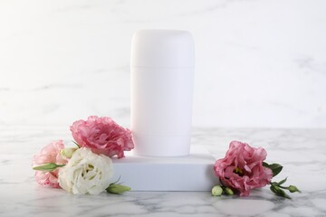 Solid deodorant and beautiful eustoma flowers on white marble table