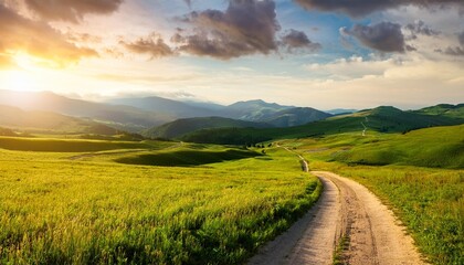 Obraz premium beautiful summer mountain rural landscape panorama of summer green field with dirt road and sunset cloudy sky