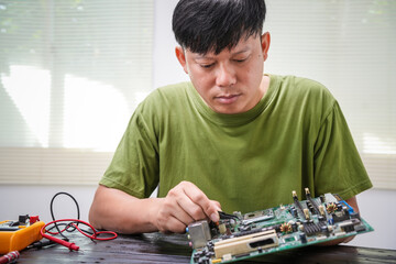Engineer, a precise computer motherboard repair technician, uses a screwdriver to change parts,...