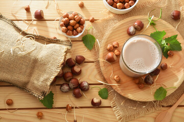 Bag and containers with hazelnuts on table with hazelnut drink