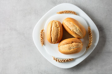 French buns and wheat ears on a marmoreal table.