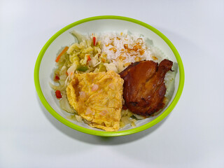 Grilled chicken thigh, plain omelette, and stir-fried cabbage mixed with sliced carrots and chillies, served with steamed rice on a plate with a green accent, against a clean white background