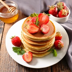 homemade delicious pancakes served with fresh strawberries and honey