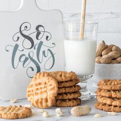 Stacks of peanut butter cookies served with milk and peanuts.