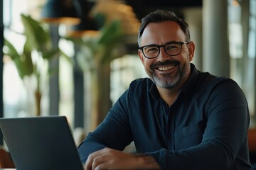 Obraz premium Happy Businessman Smiling While Working on Laptop