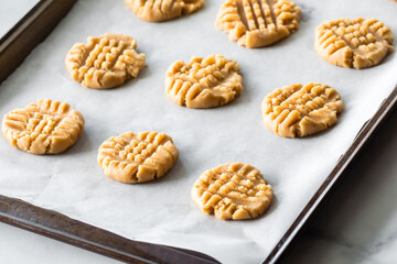 A parchment lined cookie sheet with peanut butter cookies, ready for baking.