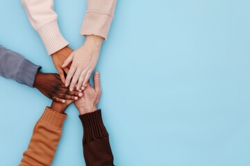 Obraz premium Top view of diverse hands reaching together over blue background, symbolizing unity, teamwork, and collaboration among different cultures.