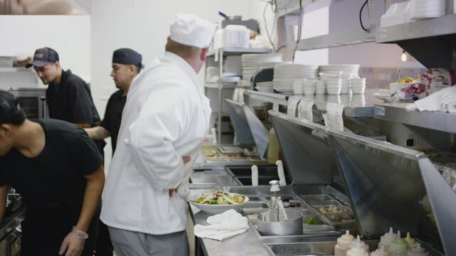 A kitchen full of chefs work to get food out to customers in a restaurant