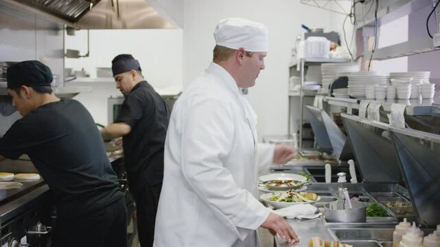 A kitchen full of chefs work to get food out to customers in a restaurant