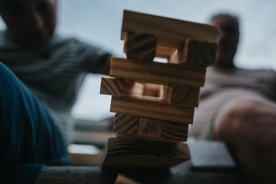 A close-up shot of a wooden block tower in a building blocks game, capturing a moment of tension and strategy among players.