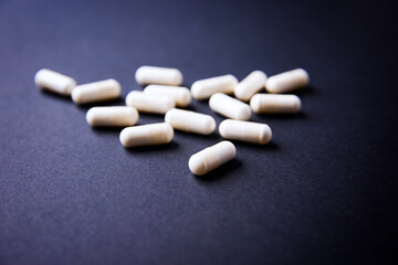 Creatine capsules on dark paper background. Soft focus. Copy space.	