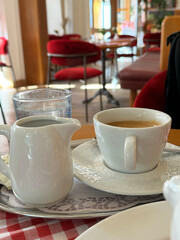 Cozy cafe table setting with coffee, creamer, and water on checkered tablecloth