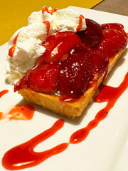 Delicious strawberry tart with whipped cream and strawberry sauce on white plate