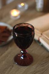 Books, lit candles, red wine, snacks and various deocration on the table. Dark academia or Halloween concept. Selective focus.