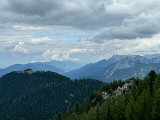 Majestic mountain range under dramatic cloudy sky in a serene forested landscape