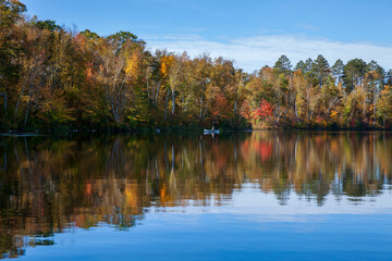 Senior man trout fishing in a solo canoe on a calm northern Minnesota lake on a beautiful autumn day