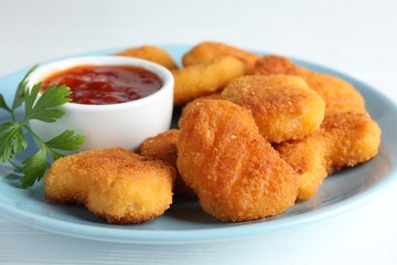 Tasty chicken nuggets with chili sauce and parsley on white table, closeup