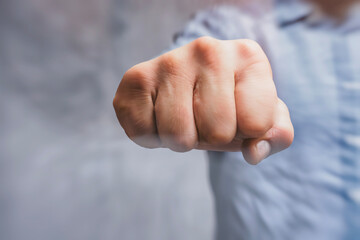 Close-up of a man in a shirt, doing a fist bump against a concrete wall. The concept of the fight.