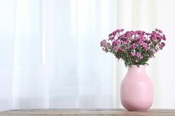 Beautiful pink flowers in vase on table indoors. Space for text