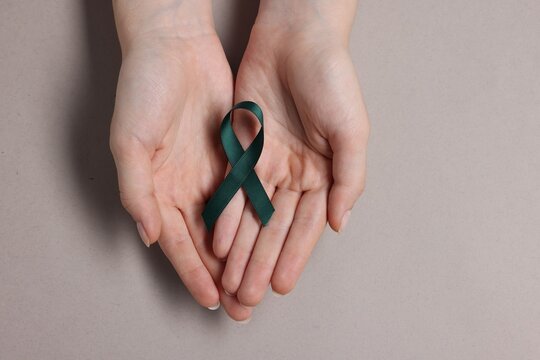 Woman with teal ribbon on grey background, top view. Ovarian cancer and gynecological disorders awareness - Powered by Adobe